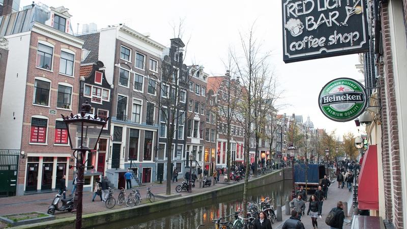 Dzielnica czerwonych latarni w Amsterdamie w ciągu dnia, z barami z widokiem na ulicę