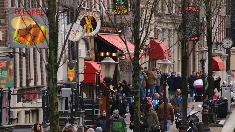 Dzielnica czerwonych latarni w Amsterdamie w ciągu dnia, ruchliwa ulica, widok na spacerujących ludzi